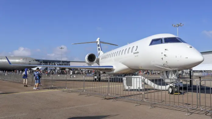 Every Bombardier price target you can look up this morning is out of date, and not by a little. President Donald Trump posted his demand that the Canadian planemaker build in the United States or stop selling there at 1:39 PM on Monday 7 September 2026 - a day when the Toronto Stock Exchange was closed for Labour Day. The most recent analyst revision on the file is dated 31 August. Every published forecast on Bombardier was therefore set in a world where nobody had threatened to close the market that supplies more than half the company's revenue.
That gap between the last forecast and the first trading session is where this piece lives. When Toronto opened on Tuesday 8 September, <strong>BBD.B printed C$295.00 against Friday's C$315.12 close - a fall of 6.4%</strong>, on a day low of C$292.34. The Street's average 12-month target of C$320.25 was set when the shares were around C$315; it now sits 8.6% above a price that has already moved. Nothing has been revised yet. What follows is what is currently projected, who projected it, and precisely when - so you can judge how much of it survives contact with the news.
Key facts: Bombardier and the Trump post
<strong>Share price:</strong> C$295.00 at 09:32 ET on 8 September 2026, down 6.4% from the C$315.12 close of 4 September (Yahoo Finance, BBD-B.TO); the 52-week range is C$150.81 to C$377.77
<strong>Performance:</strong> up roughly 90% over twelve months even after this morning's fall, and up 35% year to date to Friday's close, but 21% below the record close of C$373.41 on 27 July 2026
<strong>Average analyst target:</strong> C$320.25 across 10 analysts, with a high of C$406.00 and a low of C$191.00, and a consensus rating of Hold - 5 buy, 4 hold, 1 sell (<a href="https://www.marketbeat.com/stocks/TSE/BBD-B/forecast/">MarketBeat</a>)
<strong>The date that matters:</strong> the newest of those targets is 31 August 2026. None of them incorporates the 7 September post
<strong>Q2 2026 revenue:</strong> $2.15 billion, up 6%, on 32 aircraft deliveries, with adjusted EBITDA of $325 million at a 15.1% margin
<strong>Backlog:</strong> $21.8 billion at 30 June 2026, up $4.3 billion since year-end 2025, on a unit book-to-bill of 1.5x
<strong>Company guidance:</strong> full-year 2026 revenue above $10 billion, with free cash flow guidance raised at Q2 to more than $1 billion; available liquidity about $1.9 billion and leverage at 1.6x
<strong>US exposure:</strong> Trump claims more than 50% of revenue; Bombardier counters with 2,800 US suppliers across 47 states and $2.5 billion of annual US supplier spending
What Trump actually posted
Donald J. Trump (@realDonaldTrump) on Truth Social, 7 September 2026, 1:39 PM. The post has drawn 8,880 ReTruths, 40,000 likes and 3,424 replies. Screenshot: FinanceFeeds.
The wording matters for anyone trying to price it, because it is a demand rather than a measure. "NO MORE SELLING BOMBARDIER IN THE UNITED STATES! Their products aren't good enough!" the post begins, before making the actual ask: "If they want our Market, they must build here, and stop treating America like a 'piggybank.'" There is no executive order, no tariff schedule, no Federal Register notice and no effective date. It is a statement of intent from the President on his own platform, and the market's job this morning was to put a probability on it becoming policy.
It also did not come from nowhere. The dispute opened in January 2026, when the administration said it was decertifying Bombardier's Global Express aircraft and floated a 50% tariff on Canadian-built planes, tying the move to Transport Canada's slow certification of the Gulfstream G500, G600, G700 and G800. Monday's post repeats that grievance almost verbatim: "They even blocked Gulfstream Aerospace from doing business in Canada."
What analysts project - and when they projected it
Here is the full picture of what the sell side currently has on the file. Read the date column first.
FirmDatePrevious targetNew target
JPMorgan Chase31 August 2026C$295.00C$350.00
TD3 August 2026C$306.00C$320.00
Royal Bank of Canada31 July 2026C$383.00C$406.00
BMO Capital Markets31 July 2026C$350.00C$375.00
National Bank Financial31 July 2026C$349.00C$379.00
Two things fall out of that table that the headline consensus number hides.
<strong>First, the direction of travel was up, hard, right until the post.</strong> Four of the five most recent revisions raised the target, and JPMorgan's was a 19% increase eight days ago. Those were responses to a Q2 print that beat: revenue of $2.15 billion, adjusted EBITDA of $325 million at a 15.1% margin, and free cash flow of $228 million against a $164 million outflow in the same quarter of 2025 - a $392 million swing.
<strong>Second, the C$320.25 average is dragged down by stale outliers, not by caution about Trump.</strong> The five firms above cluster between C$320 and C$406. The average includes a C$191 low target that is 35% below the current price and looks like a forecast nobody has refreshed. Read the panel rather than the mean and the pre-post Street was positioned nearer C$350 than C$320. Other aggregators using wider panels published averages closer to C$349-355 for the same reason. This is why "the consensus" is not one number and should never be quoted as though it were - the same problem we ran into pricing the Fed this week in our <a href="https://financefeeds.com/gold-price-holds-4400-fed-hike-odds-51-5/">gold and Fed rate analysis</a>, where three venues disagreed by fifteen points on the same event.
The consensus rating is Hold: five buys, four holds and one sell. On the numbers as they stood on Friday, that Hold implied roughly 1.6% of upside. On this morning's C$295.00 it implies 8.6% - purely because the price fell, not because anyone became more optimistic.
Where the Street sits versus the price. All three target levels were set before Trump's 7 September post. Source: Yahoo Finance daily closes plus the live 8 September print; targets per MarketBeat's compilation of 10 analysts.
What the company itself projects
Bombardier's own guidance is the other half of "what is projected", and it has been revised more recently than most of the analyst file. For 2026 the company guides to revenue above $10 billion, and at the second-quarter results on 30 July it <em>raised</em> free cash flow guidance to more than $1 billion, from a previous range of $600 million to $1 billion.
The balance sheet behind that is no longer the fragile one investors remember from the turnaround years: available liquidity of approximately $1.9 billion and an adjusted net debt to adjusted EBITDA ratio of 1.6x, approaching the company's 1.5x target. Chief executive Éric Martel framed the quarter around execution rather than macro: "Our profitability growth, record services revenue and robust free cash flow are all rooted in the quality of our team and their collective commitment to our customers."
The single most important number for judging the Trump risk is the backlog. It stood at <strong>$21.8 billion on 30 June 2026, up $4.3 billion since year-end</strong>, on a unit book-to-bill of 1.5x - meaning Bombardier booked half as many aircraft again as it delivered. Services revenue hit a record $674 million, up 14%, and services is a recurring, installed-base business that a sales ban does not touch for years.
Why the shares fell 6% and not 30%
A threat to close off more than half of a company's end market sounds like it should be worth far more than 6.4%. Three structural facts explain why the market is discounting it rather than capitulating to it, and they are the same three that any revised target will have to weigh.
<strong>The near-term revenue is already sold.</strong> A $21.8 billion backlog against roughly $10 billion of annual revenue is more than two years of production spoken for. An import restriction would hit new orders first and deliveries second; it would take time to reach the income statement, and time is what gives a negotiation room to run.
<strong>The product is substantially American.</strong> Bombardier's response to the post leaned on this hard, and the specifics are checkable: engines, avionics and other key systems from US suppliers, 2,800 US suppliers across 47 states, roughly $2.5 billion of annual US supplier spending, employees in more than 20 states - and, pointedly, "the wings for the world's fastest business jet are made by American workers at Bombardier's facility in Red Oak, Texas." A ban on Bombardier sales in the US is also a tax on a Texas wing plant, which is a politically awkward shape for the policy to take.
<strong>There is no instrument yet.</strong> January's threatened 50% tariff and decertification did not arrive as written either. Markets have learned to price the distance between a Truth Social post and a Federal Register notice, and this morning's 6.4% is roughly what that discount looks like: real, but far short of pricing a ban as fact.
The counter-argument deserves equal weight. Business jets are discretionary, high-ticket purchases with long lead times, and uncertainty alone can freeze a US buyer's decision without any policy ever being signed. That is the channel through which this becomes a numbers story rather than a headline: not a ban, but a quarter or two of soft US orders showing up in the book-to-bill. The demand backdrop for the sector, and the cross-border trade pressure driving it, is the same one we traced in our coverage of <a href="https://financefeeds.com/the-gulf-export-disruption-is-now-a-bond-story-oil-yields-and-the-inflation-repr/">how supply shocks reprice through to yields</a>.
What to watch next
<strong>1. Revisions, and how fast they come.</strong> The first analyst note that explicitly prices the post will reset the range. Watch whether the C$191 low gets refreshed - a stale outlier being updated would move the average more than any single new bull case.
<strong>2. Any actual instrument.</strong> An executive order, a tariff schedule, a decertification notice or a Section 232 action would change this from rhetoric to policy. Until one of those exists, the 8.6% gap between the price and the average target is a bet on nothing happening.
<strong>3. The Q3 book-to-bill on 30 October or thereabouts.</strong> The 1.5x from Q2 is the cleanest single number in the story. If US buyers pause, it shows up there first, before it ever reaches revenue or guidance.
<strong>4. Ottawa's response.</strong> The post explicitly ties the grievance to Canadian treatment of Gulfstream and of US banks. A Transport Canada decision on the Gulfstream certifications would remove the stated justification, which is the fastest de-escalation path available.
Having covered this file since the January decertification threat, our read is that the market is pricing roughly what the evidence supports: a real risk, a low probability of the maximal version, and a company whose backlog buys it time to negotiate. What nobody can price yet is the revision cycle - and until the sell side updates, every target you read on Bombardier describes a world that ended at 1:39 PM on Monday. For the wider list of tickers moving on this administration's trade actions, see our <a href="https://financefeeds.com/energy-stocks-ccj-99-ceg-279-eqt-54-vst-147/">round-up of the industrial and energy complex</a> and our <a href="https://financefeeds.com/nvidia-nvda-stock-prediction-365-bull-145-bear-sp-500/">Nvidia analysis</a> on how policy risk gets discounted in practice.
Frequently asked questions
What is the Bombardier stock price prediction after Trump's announcement?
The published average 12-month target is C$320.25 from 10 analysts, with a high of C$406.00 and a low of C$191.00 and a consensus rating of Hold. The critical caveat is timing: the newest of those targets is dated 31 August 2026, a week before Trump's 7 September post, so none of them prices a US sales ban. Against the C$295.00 print on 8 September, the average implies 8.6% upside.
What did Trump say about Bombardier?
In a Truth Social post at 1:39 PM on 7 September 2026 he wrote "NO MORE SELLING BOMBARDIER IN THE UNITED STATES! Their products aren't good enough!" and claimed over 50% of the company's revenue comes from the US. His actual demand was conditional: "If they want our Market, they must build here." No executive order, tariff schedule or effective date accompanied the post.
How much did Bombardier stock fall?
BBD.B opened the 8 September session at C$295.00 against the 4 September close of C$315.12, a decline of 6.4%, with a day low of C$292.34. The Toronto Stock Exchange was closed on 7 September for Labour Day, so this was the first opportunity for the market to price the post.
How much of Bombardier's revenue comes from the United States?
Trump asserted more than 50%. Bombardier did not dispute the figure in its response, choosing instead to stress its American footprint: 2,800 US suppliers across 47 states, about $2.5 billion of annual spending with those suppliers, employees in more than 20 states, and wings for its fastest business jet built in Red Oak, Texas.
What is Bombardier's guidance for 2026?
The company guides to full-year 2026 revenue above $10 billion and raised its free cash flow guidance at the Q2 results to more than $1 billion, from $600 million to $1 billion previously. It reported available liquidity of roughly $1.9 billion and an adjusted net debt to adjusted EBITDA ratio of 1.6x against a 1.5x target.
Does the backlog protect Bombardier from a US sales ban?
Partly, and for a while. The order book stood at $21.8 billion on 30 June 2026, more than two years of revenue at the current run rate, and grew $4.3 billion in the first half on a 1.5x unit book-to-bill. A restriction would suppress new US orders long before it reduced deliveries, which is the main reason the equity fell 6% rather than pricing the threat as an accomplished fact.
<em>This article is analysis, not investment advice. Prices are as of 09:32 ET on 8 September 2026 and the market was open at the time of writing.</em>